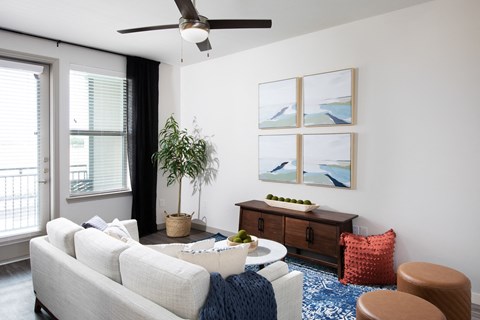 a living room with a white couch and a table and a ceiling fan